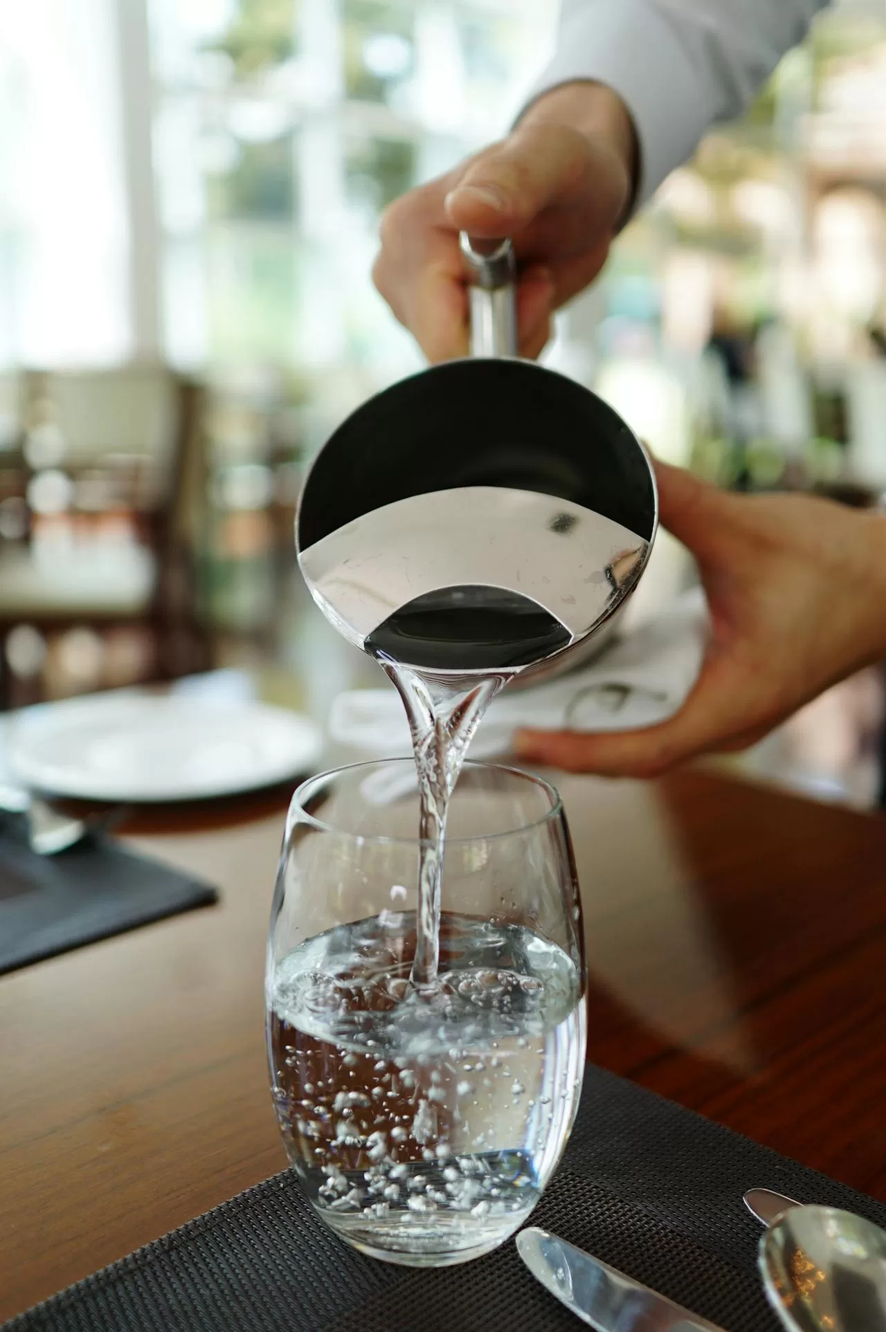 Person pouring filtered water into a glass